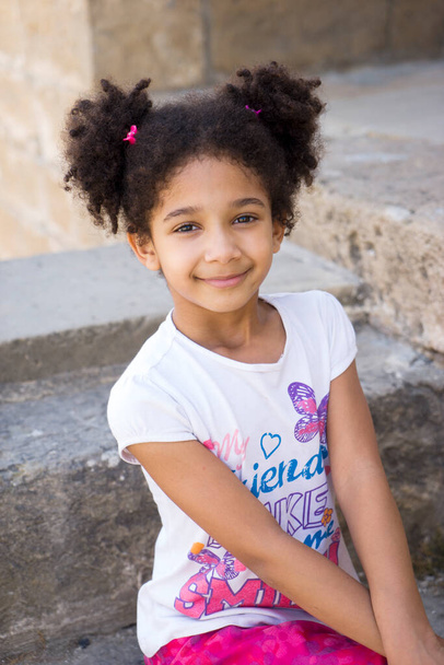 Klein bruin meisje Afro-Amerikaanse verschijning met krullend haar lachen hardop en kijken naar de camera - Foto, afbeelding