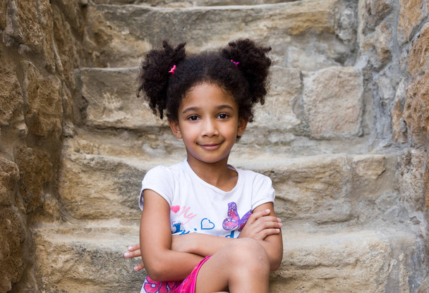 小さな茶色の女の子アフリカ系アメリカ人の外観とともに巻き毛笑います大声でと見てカメラ - 写真・画像