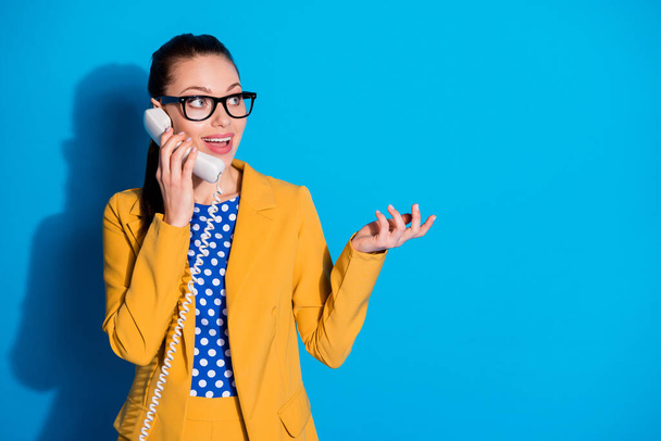 Portrait of excited marketer banker assistant girl call telephone friend tell talk say speak business news wear yellow dotted blazer jacket isolated over blue color background - Φωτογραφία, εικόνα