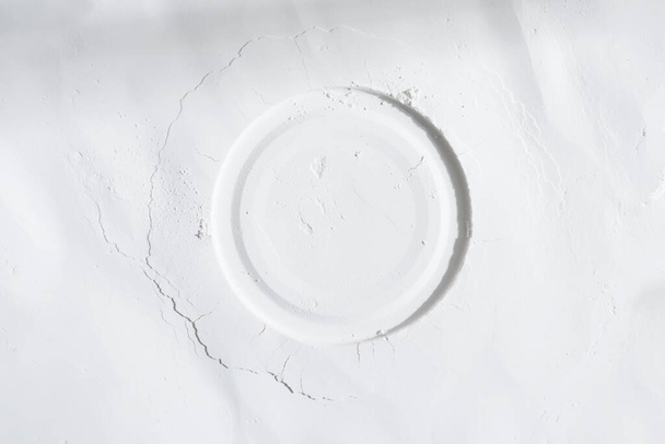 Koristeellinen pyöreä runko valkoisesta jauheesta, jauhoista tai hiotusta liitusta vaaleanharmaalla pohjalla varjolla, kopioi tilaa. - Valokuva, kuva