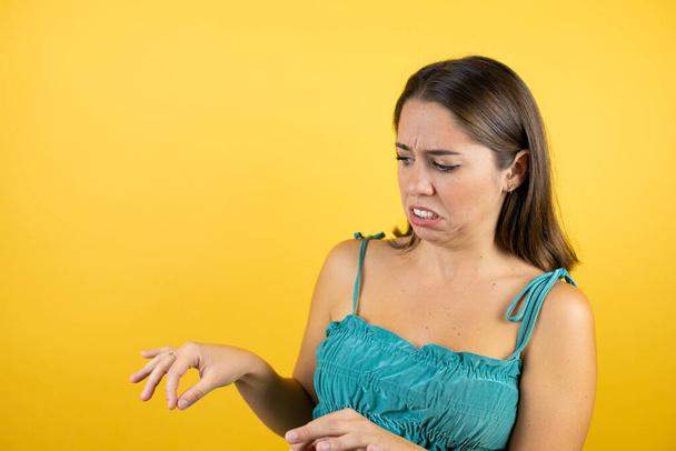 Young beautiful woman over isolated yellow background disgusted expression, displeased and fearful doing disgust face because aversion reaction. With hands raised. Annoying concept - Photo, Image