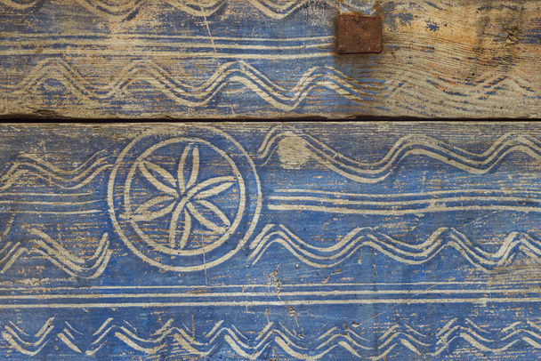 Το παλιό ξύλινο μπαούλο είναι βαμμένο με μπλε μπογιά και διακοσμημένο με λευκό στολίδι. Κοντινό πλάνο. Ιστορικό - Φωτογραφία, εικόνα