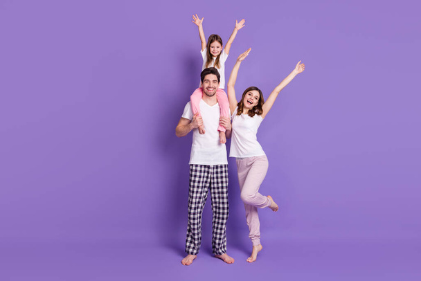 Full length body size view of three person cheery family dad carrying offspring daughter wearing pajama rising hands up having fun weekend isolated bright vivid shine vibrant violet color background - Φωτογραφία, εικόνα
