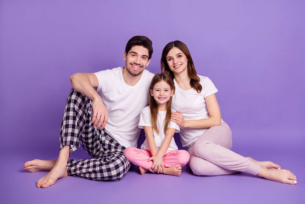 Portrait of cheerful family dad mom offspring daughter wearing cozy comfort pajama sitting on floor embracing stay home quarantine isolated on bright vivid shine vibrant violet color background - Photo, Image