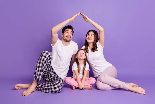 Portrait of nice cheerful full family dad mom offspring daughter wearing pajama sitting on floor showing roof flat house isolated on bright vivid shine vibrant violet color background - Photo, Image