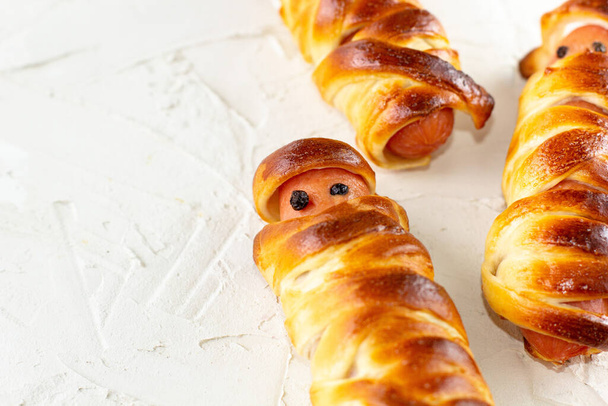 Momies de saucisses effrayantes dans la pâte pour la fête des enfants. drôle fou Halloween nourriture pour enfants sur fond blanc - Photo, image