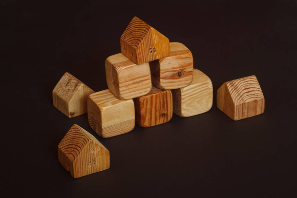 Dřevěné stavební kameny pro děti. Hračková budova z dřevěných kostek na tmavém pozadí - Fotografie, Obrázek