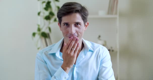 Portrait of humorous comical man, looking at camera, surprised pleasantly shocked, covers his open mouth with hand in amazement, laughs toothy with joke. Close up emotional male face smiling carefree - Footage, Video