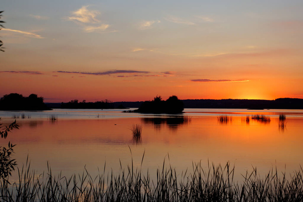         Csendes este a tó felett. Fényes naplemente és kacsák a vízfelszínen. Nyár.                        - Fotó, kép