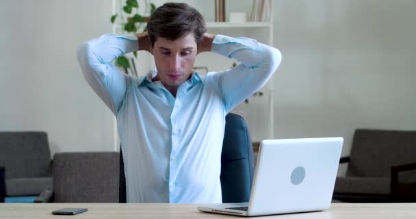 Gefrustreerde jonge zakenman voelt hoofdpijn, pijn, denkt na over moeilijk probleem, maakt zich zorgen over slecht nieuws of verlies van geld, stress van hard werken, faalt zittend aan tafel op kantoor - Video
