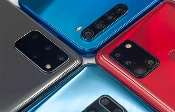 Чотири різнокольорові сучасні смартфони з різними модулями фотоапаратів крупним планом
.  - Фото, зображення