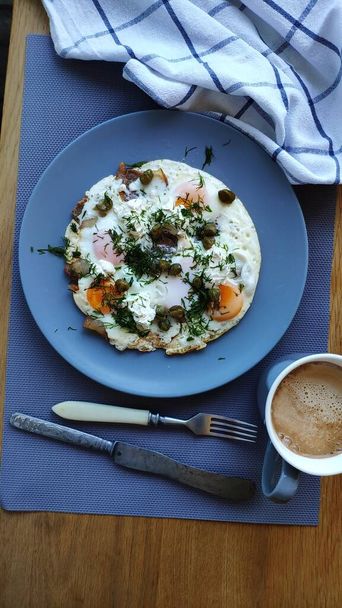 Gebakken eieren met kappertjes en kruiden en koffie met room, ketogeen ontbijtconcept, selectieve focus - Foto, afbeelding