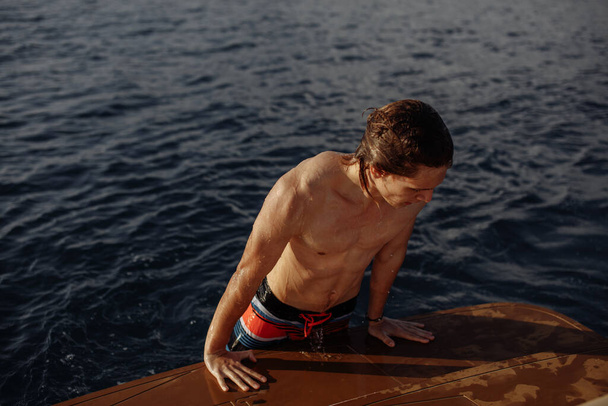 Young caucasian hipster guy enjoying journey on yacht deck sailing the sea. - Zdjęcie, obraz