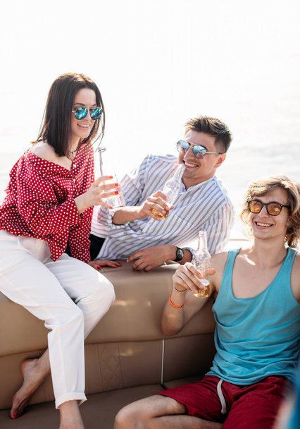 yacht drinking beers while talking Group of friends having party on sailing boat - Фото, изображение