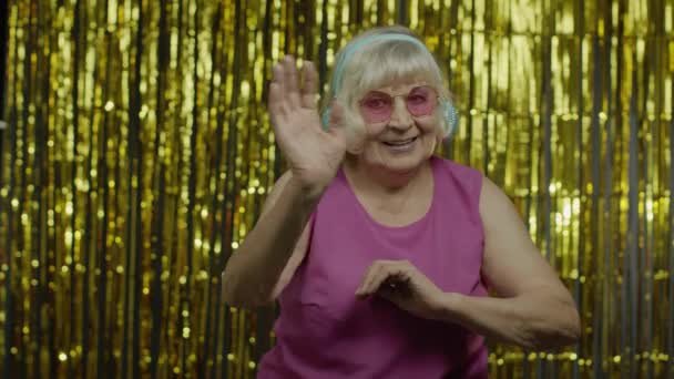 Vriendelijke oudere oude vrouw zwaaiende handen kijken naar de camera met een tand glimlach, gedag zeggen, groeten - Video