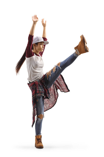 Full length profile shot of a female dancing hip-hop with one leg lifting up isolated on white background - 写真・画像