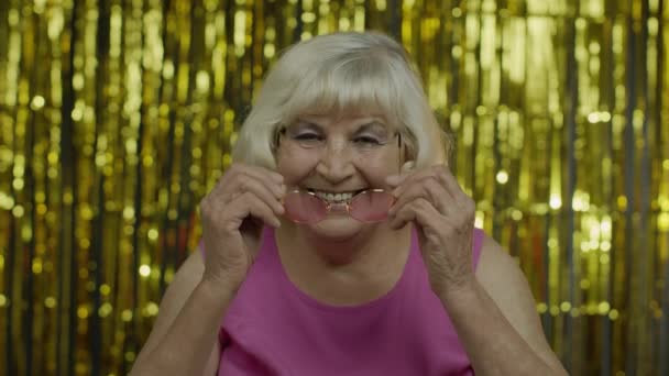 Vieille femme âgée positive en lunettes de soleil jouissant, souriant, satisfait de la vie, de la bonne humeur, du succès - Séquence, vidéo