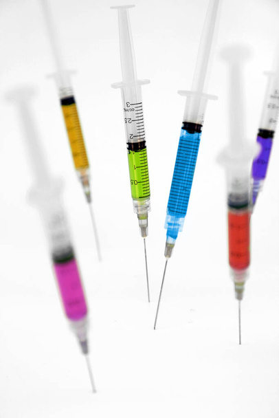 Verschiedene Impfstoffe in Spritzen auf weißem Hintergrund.  - Foto, Bild