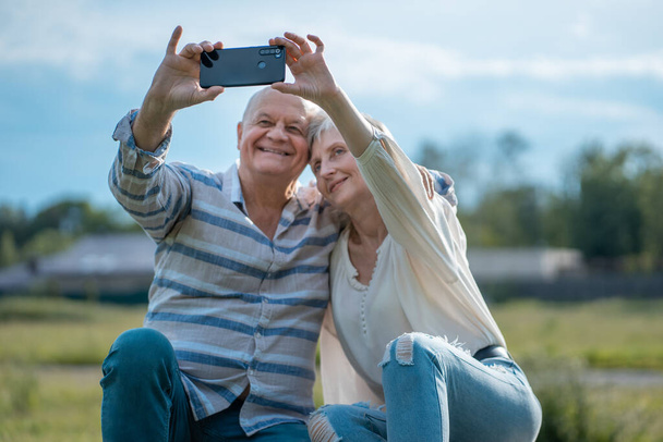 šťastný starší pár dating, přičemž selfie a bavit se venku - Fotografie, Obrázek