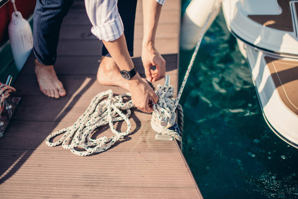 Yachtsman tying up motor boat at pier. - Fotoğraf, Görsel