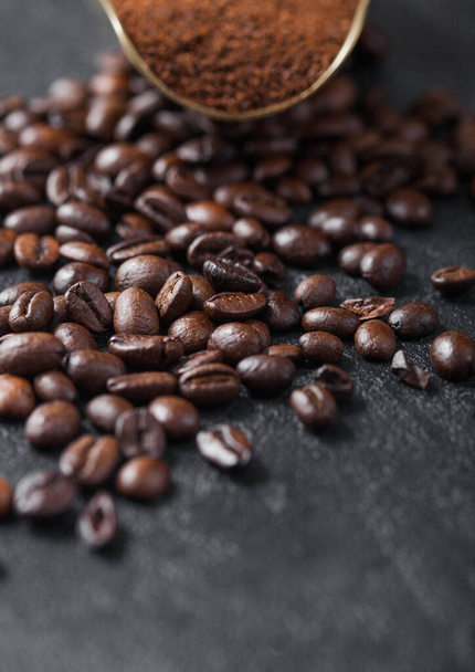Fresh raw organic coffee powder and beans in vintage steel scoop on black background. Macro - Zdjęcie, obraz