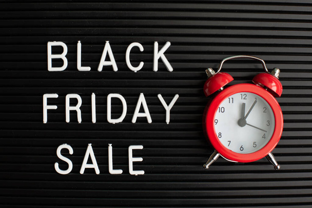 White text Black Friday Sale on black letter board and alarm clock, closeup. Season sales time. Flat lay - Photo, Image