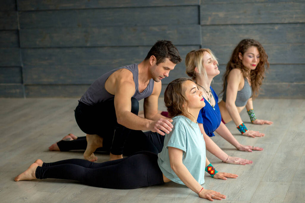 Male Yoga instructor teaching yoga to three young women - Fotoğraf, Görsel
