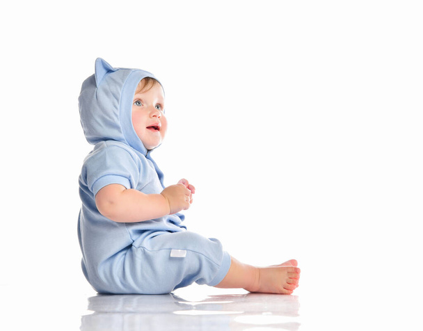Baby wearing funny blue suit sit on studio floor - Foto, afbeelding