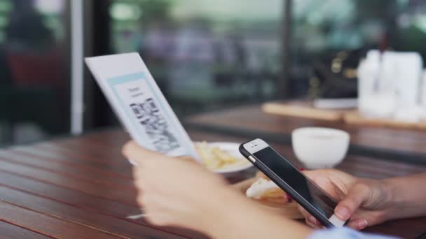 Dłonie kobiet używają telefonu do skanowania kodu QR, aby wybrać menu żywności. Zeskanować, aby uzyskać zniżki lub zapłacić za jedzenie. Koncepcja korzystania z telefonu do przelewu pieniędzy lub płatności online bez gotówki. - Materiał filmowy, wideo