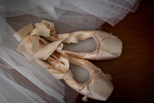 Ballet pointe shoes with a tulle tutu on a wooden tabletop - Fotografie, Obrázek