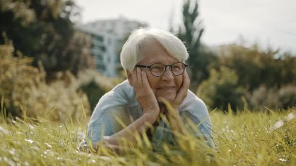 senior feliz mujer de pelo gris disfrutando del soleado día de otoño en el parque - Imágenes, Vídeo