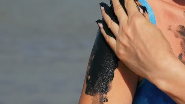 Gyógyító fekete orvosi sár vonatkozik a karos nő a tó sós víz. Sós fekete piszok az egészségügyi és bőrproblémákkal küzdőknek. Pihenj a gyógyfürdőben. Bőrradír kozmetikai kezelés - Felvétel, videó