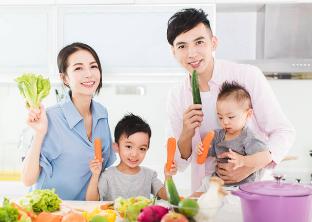 キッチンで健康的な食べ物を見せる幸せな家族 - 写真・画像