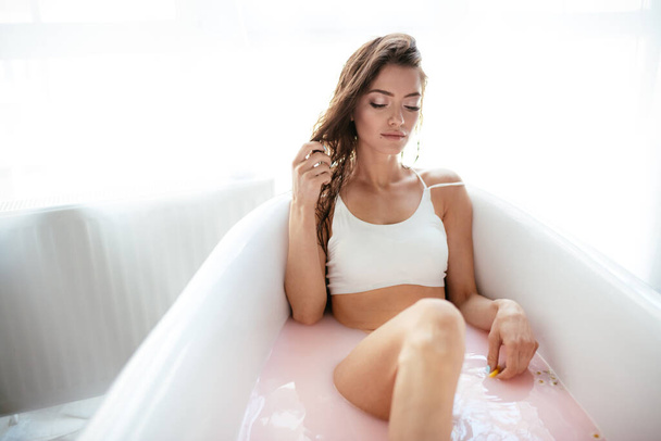 Woman relaxing in milky bath in spa resort. Wellness and Wellbeing concept - Foto, Bild