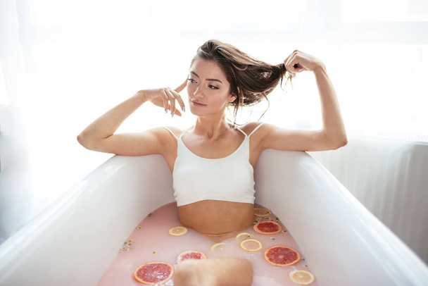 Woman relaxing in milky bath in spa resort. Wellness and Wellbeing concept - 写真・画像