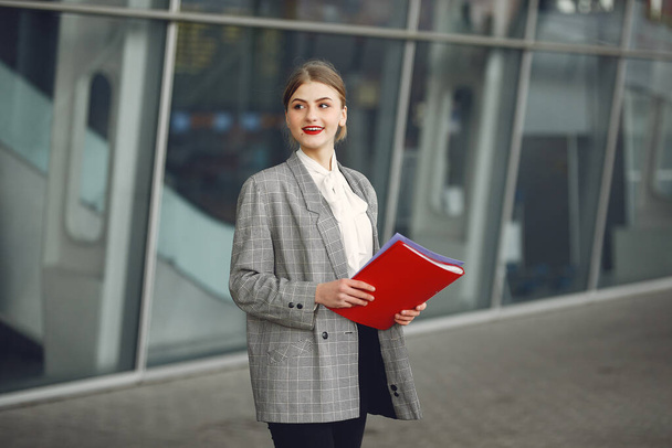 Woman standing in a city with a red folder - Zdjęcie, obraz