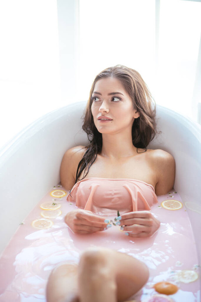 Женщина отдыхает в молочной ванне в спа-центре. Концепция здоровья и благополучия - Фото, изображение