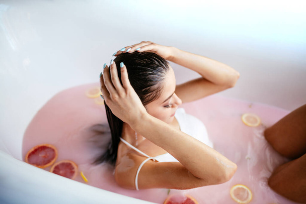 Woman relaxing in milky bath in spa resort. Wellness and Wellbeing concept - Фото, изображение