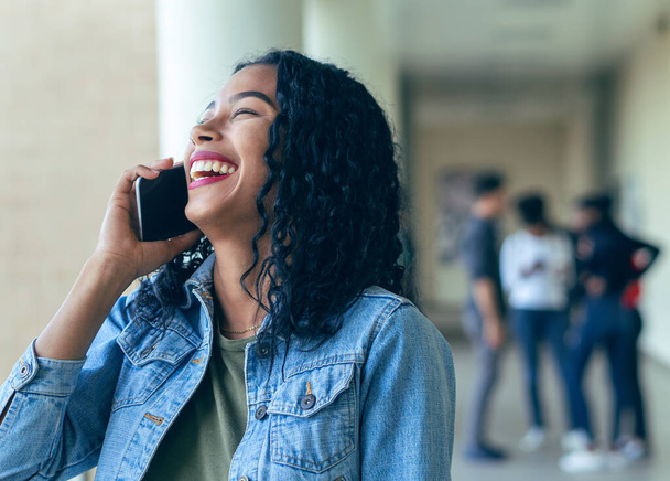 Une étudiante riant avec un appel avec ses camarades de classe en arrière-plan - Photo, image