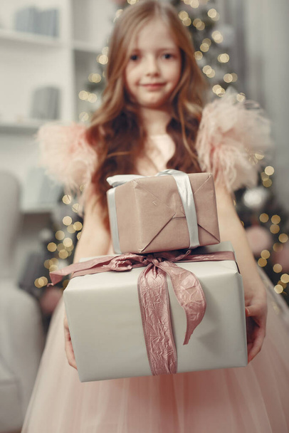 Little girl near christmas tree in a pink dress - Фото, изображение
