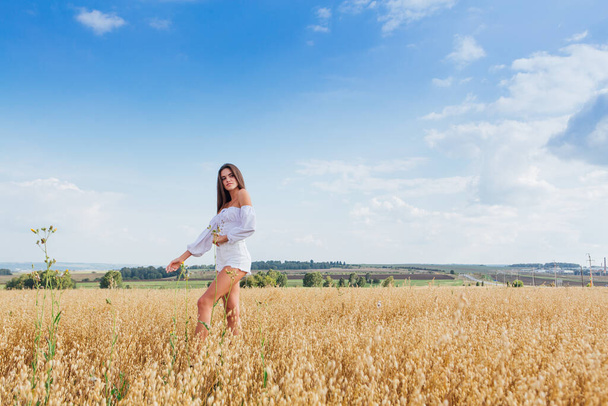 Young beautiful woman relaxing at golden oat field. - Foto, afbeelding