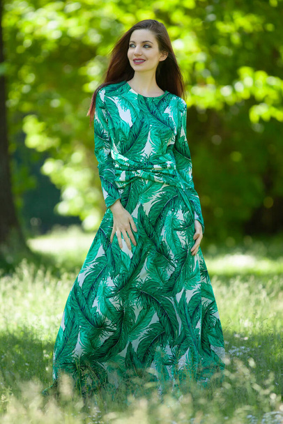 молода жінка в довгій зеленій сукні в саду
 - Фото, зображення
