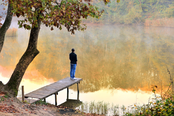 秋の風景の若者が直面している水に反映 - 写真・画像