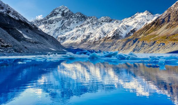 Glaciar Hooker derritiéndose con el nevado Monte Cook en la distancia reflejándose en el lago y un hermoso cielo azul claro - Foto, imagen