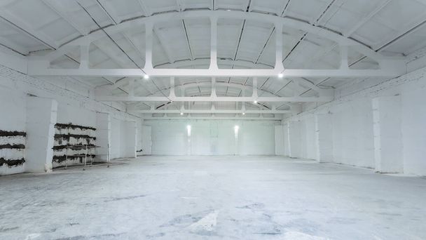 Интерьер промышленного здания с белыми кирпичными стенами, бетонным полом и пустым пространством для демонстрации продукции или промышленного фона - Фото, изображение