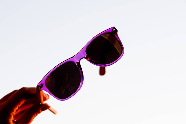 Klassieke zonnebril model vasthouden met de hand schieten in een zomerdag close-up. Selectieve focus - Foto, afbeelding