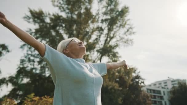 Nyugdíjas nő nyújtózkodik a parkban ősszel. Lassú mozgás. - Felvétel, videó