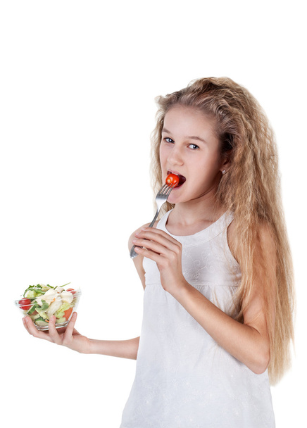 Χαριτωμένο αρκετά όμορφο κοριτσάκι με μακριά μαλλιά τρώει σαλάτα λαχανικών, χρησιμοποιώντας πιρούνι - έννοια της υγιεινής διατροφής - Φωτογραφία, εικόνα