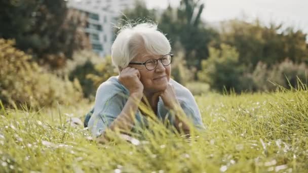 vanhempi eläkkeellä oleva nainen nauttimassa aurinkoisesta syyspäivästä puistossa - Materiaali, video