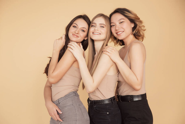 Groep multiraciale vrouwen staan knuffelen en op zoek camera. vriendschap poseren samen aziatisch, blond, brunette - Foto, afbeelding